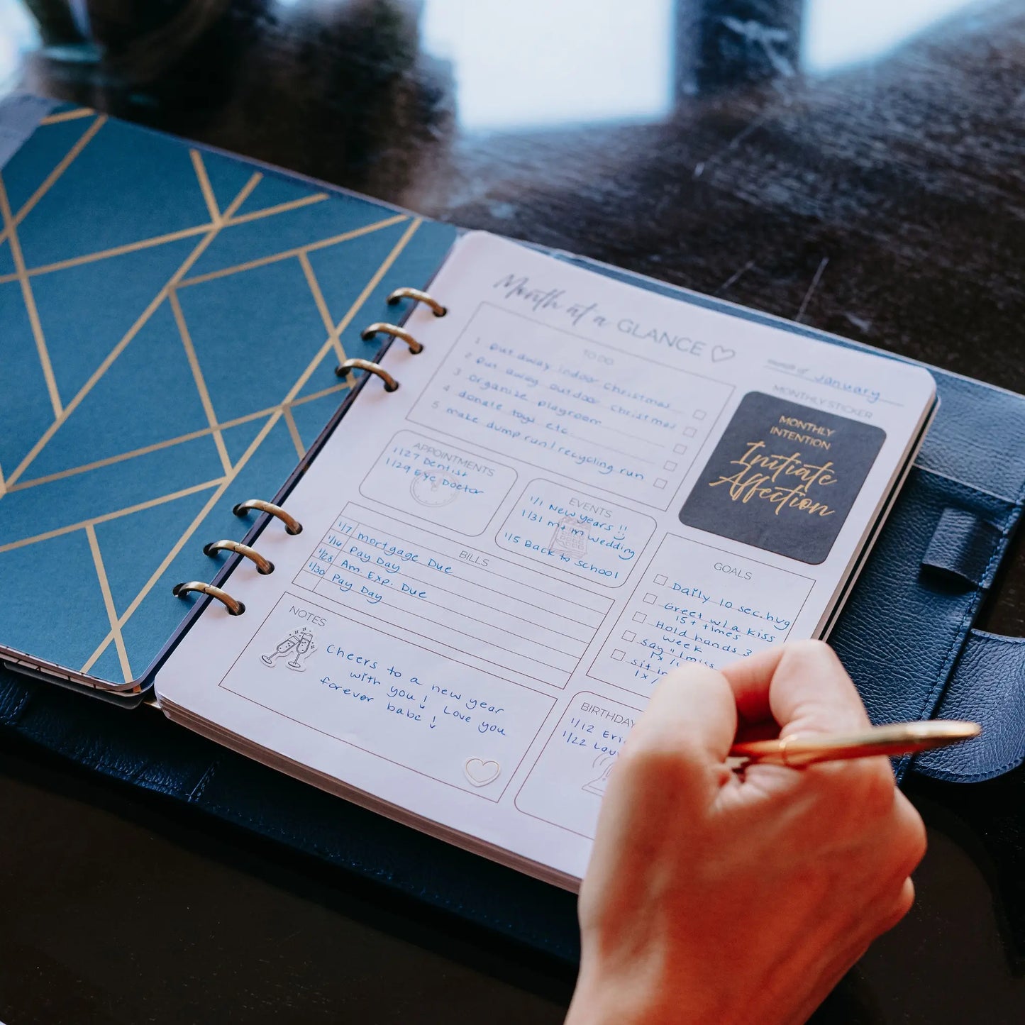 Person writing on Month at a Glance planning page inside the Honor Him Luxe Marriage Transformation System