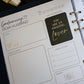 A close-up of a Honor Him Thru Intimacy Affirmation Sticker Book page with a 'Good morning, Dear Husband' layout. The page includes fields for notes, today's events, a honey do list, dinner, a daily affirmation sticker that reads 'You are an amazing lover' in gold on black, and a gold 'wink' doodle.