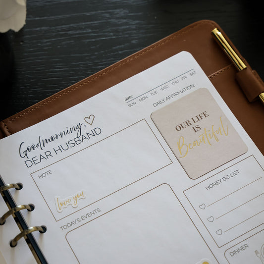 Honor Him Thru Words Affirmation Sticker Book displayed inside the Honor Him marriage planner with affirmation stickers.