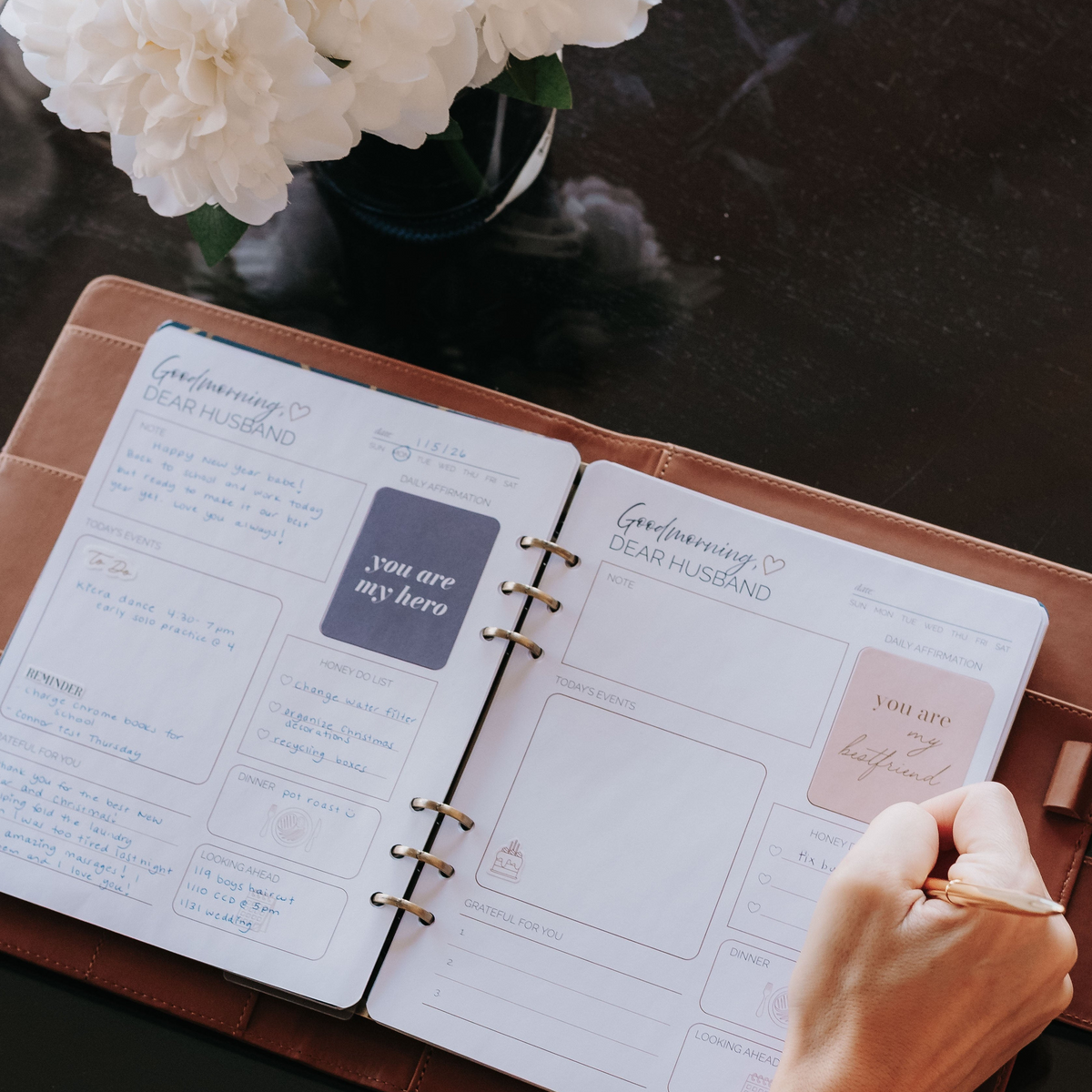 Open cognac leather padfolio with a marriage planner, handwritten notes, and daily affirmations on a table