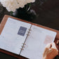 Person using the Honor Him guided Christian marriage transformation system inside a cognac leather padfolio